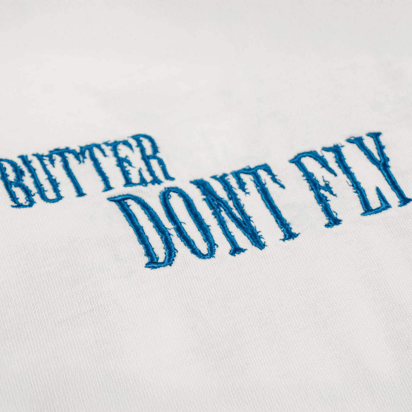 Extreme close-up af butter dont fly hvid front broderi